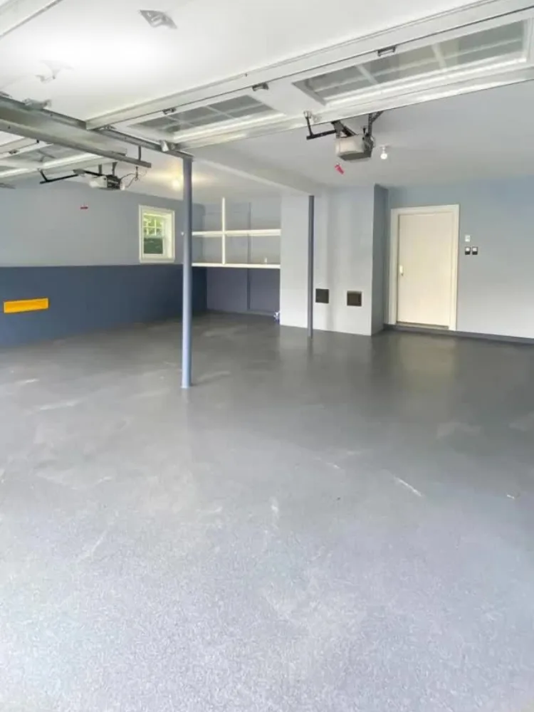 A wide view of a residential interior showing a gray garage floor epoxy finish and custom blue and gray wall painting.