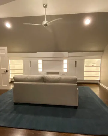 Wide angle view of a custom attic media center installed under a pitched roof in a modern loft.