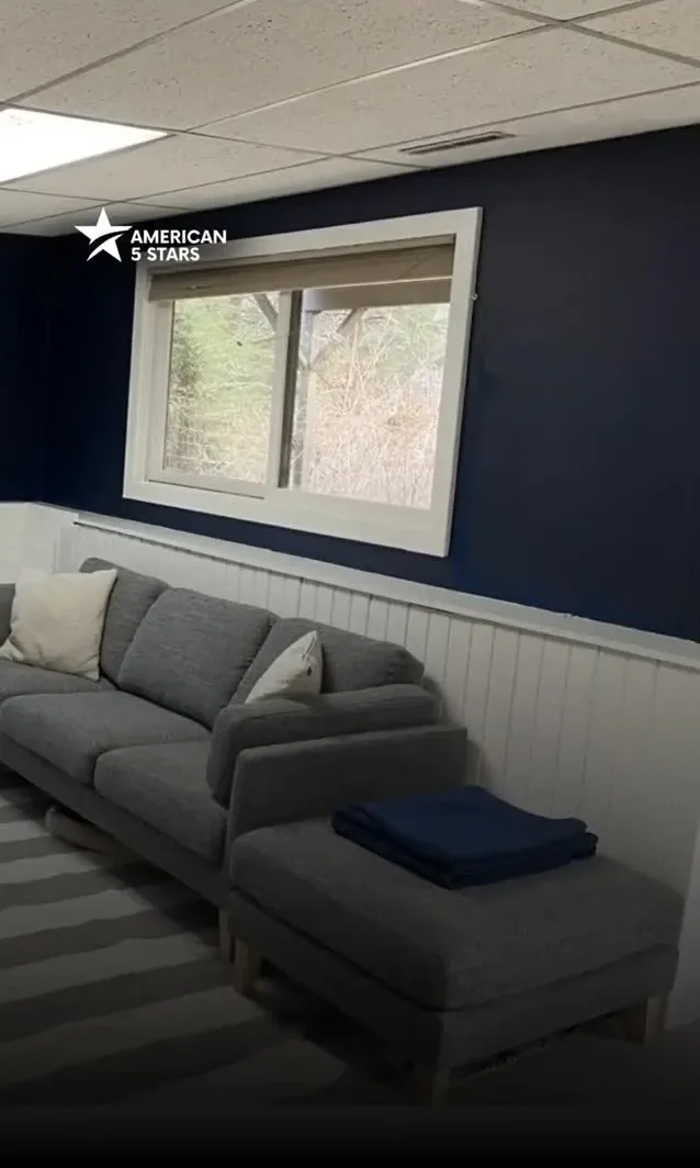 Interior wall painting completion showing a grey sofa against a newly painted deep blue wall with white lower wainscoting.