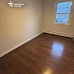 Completed professional hardwood installation in a bedroom showing dark-stained wood planks and clean baseboard transitions.