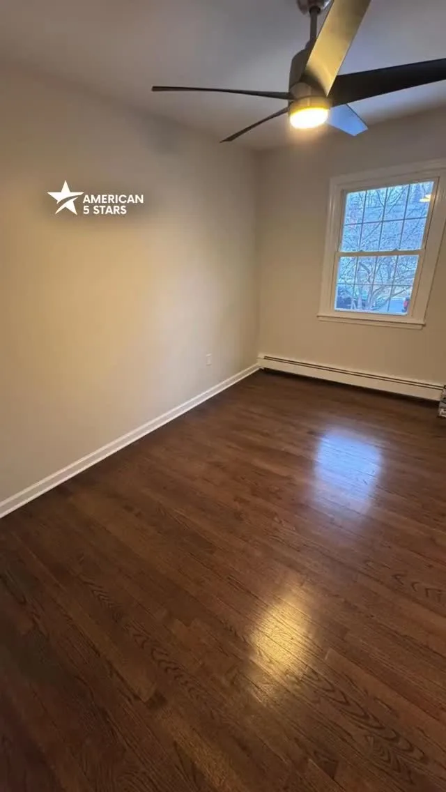 Completed professional hardwood installation in a bedroom showing dark-stained wood planks and clean baseboard transitions.