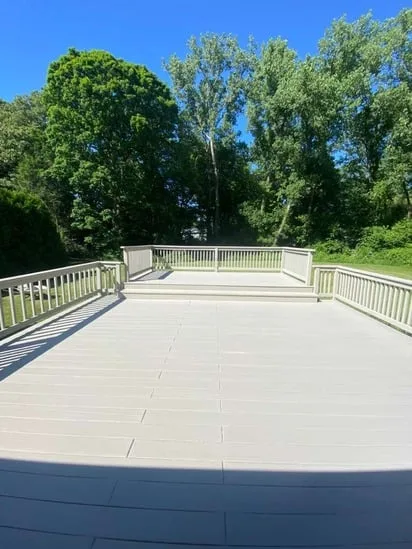 Wide perspective of the main deck platform facing the woods after a full residential deck restoration.